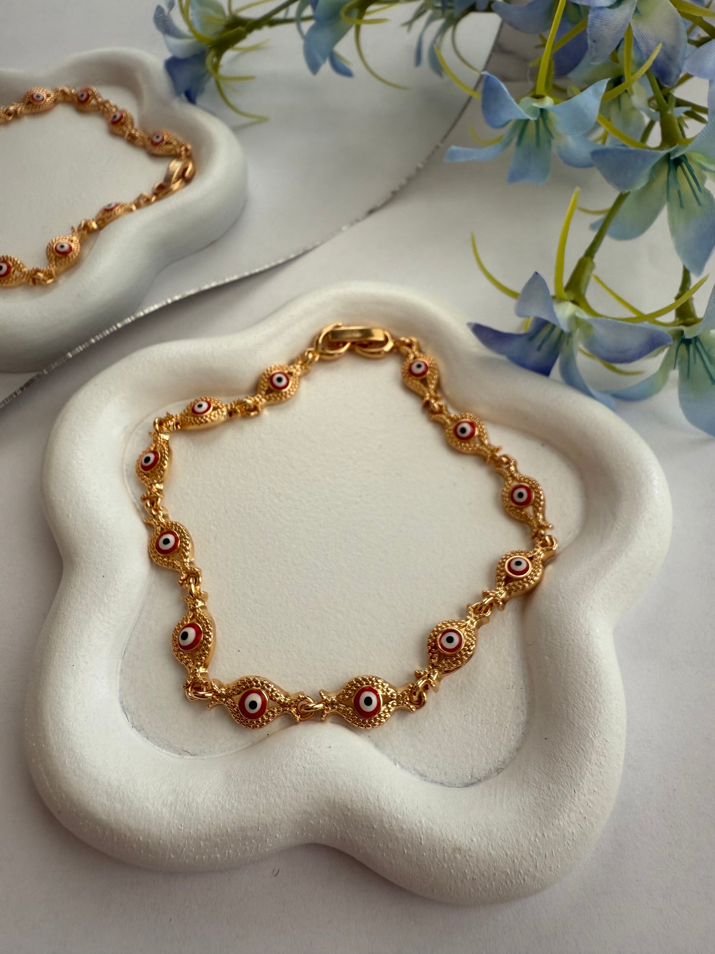 Pulsera Roja de Ojitos Vintage – Detalle con textura dorada